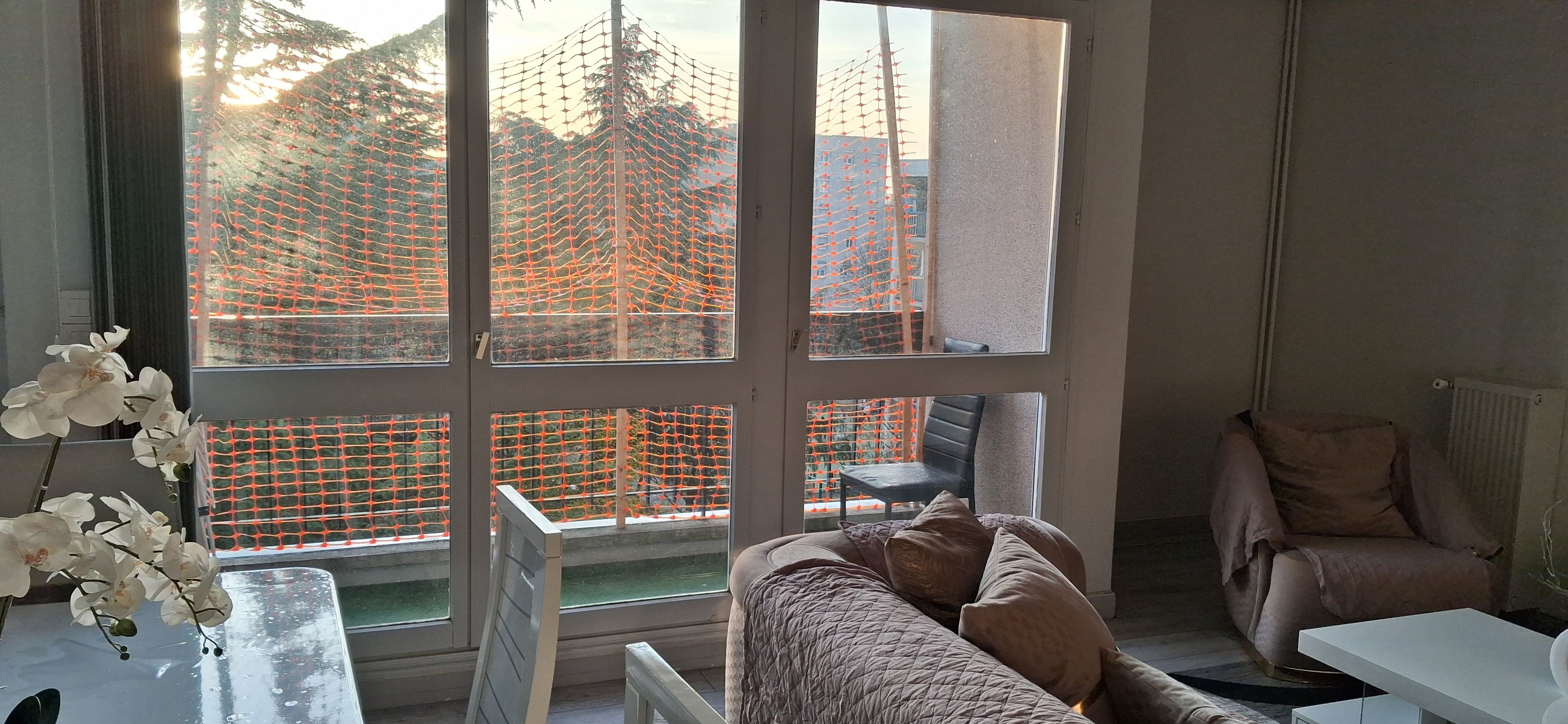Une pièce avec une grande fenêtre, une chaise, un lit et une table.