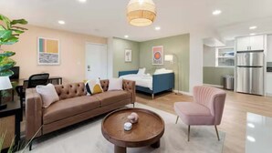 Ein modernes Wohnzimmer mit Sofa, Sesseln, Couchtisch und einer Pendelleuchte.