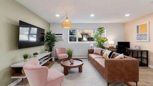 Ein modernes Wohnzimmer mit Flachbildfernseher, einer Couch, einem Couchtisch und einer Pendelleuchte.