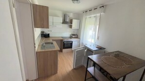 A compact kitchen with a sink, stove, and a small dining area with a table. - Apartment 'Liki' with Wi-Fi (Siegen)