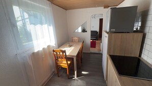 A kitchen with a black stove, wooden cabinets, and a dining area with a table and chairs. - Apartment 'Liki' with Wi-Fi (Siegen)