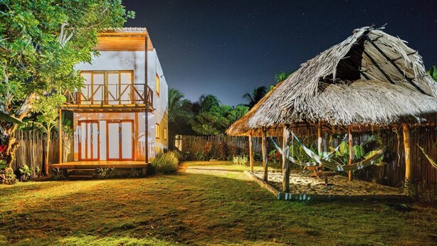 A modern house with a balcony and a traditional hut.