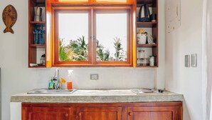 A kitchen with wooden cabinets, a window with a view, and a trash bin.