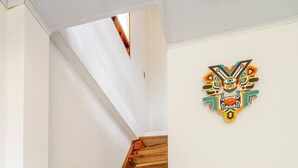 A wooden staircase leading to a landing, a teal sofa, and a wall-mounted decorative piece.