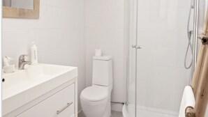 Een badkamer met een wit wastafel, toilet en douche.