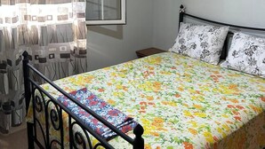 A bedroom with a bed, curtains, a window, a map on the wall, and a ceiling fan.