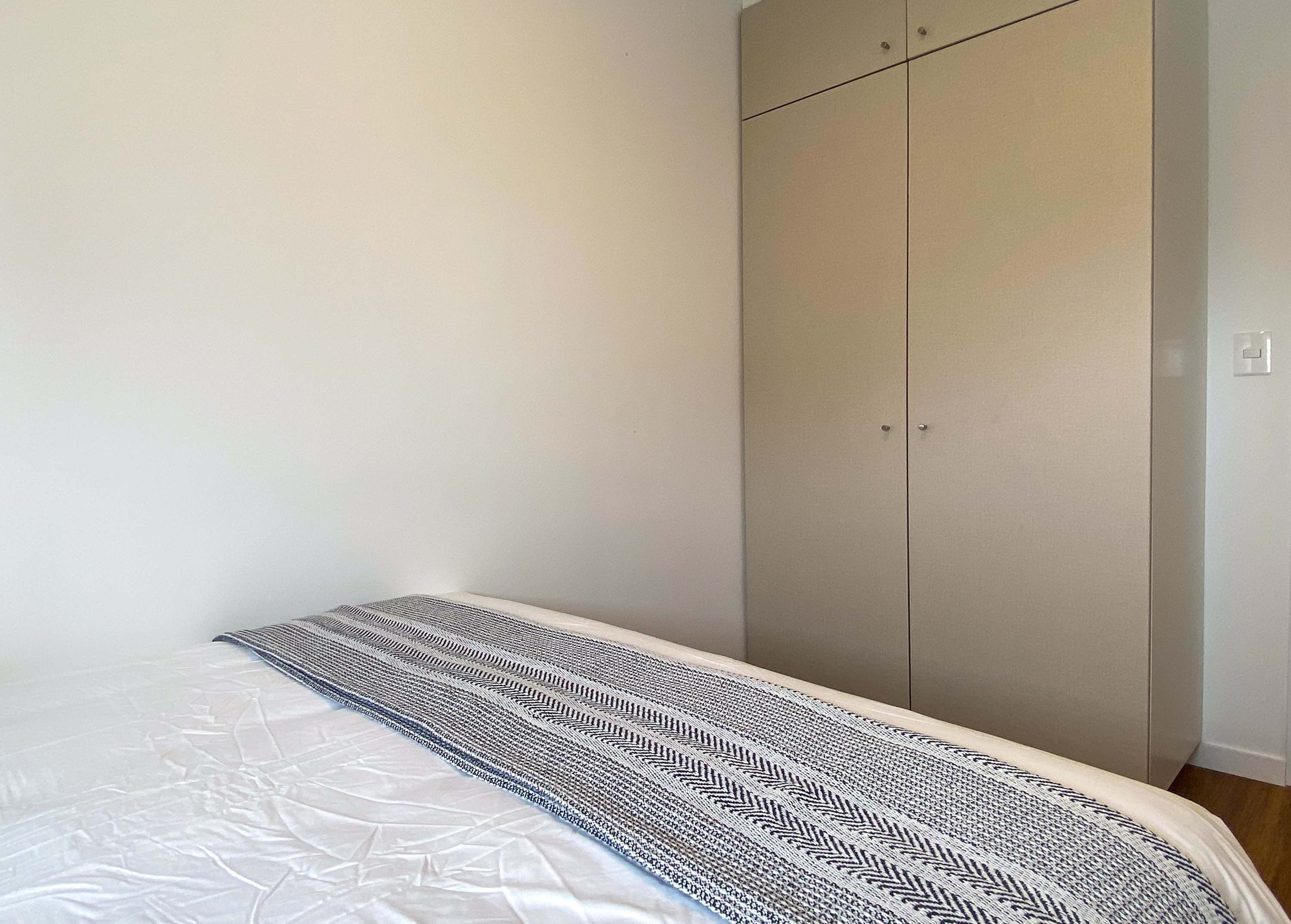 Une chambre à coucher avec un lit, une couvre-lit à motifs et une grande armoire.