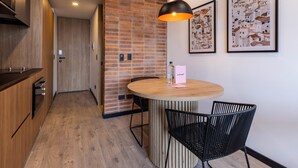 A modern kitchen with wooden cabinets, a brick accent wall, and a round dining table with black chairs. - w Unique Loft in Parque Virrey (Bogotá)