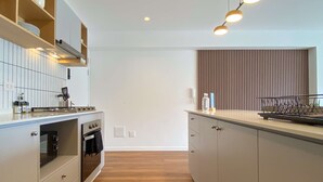A modern kitchen with a built-in oven, a microwave, and a stovetop. There are wooden cabinets and a countertop with a dish rack. - w Upscale 2BR w Balcony View in Miraflores (Lima)