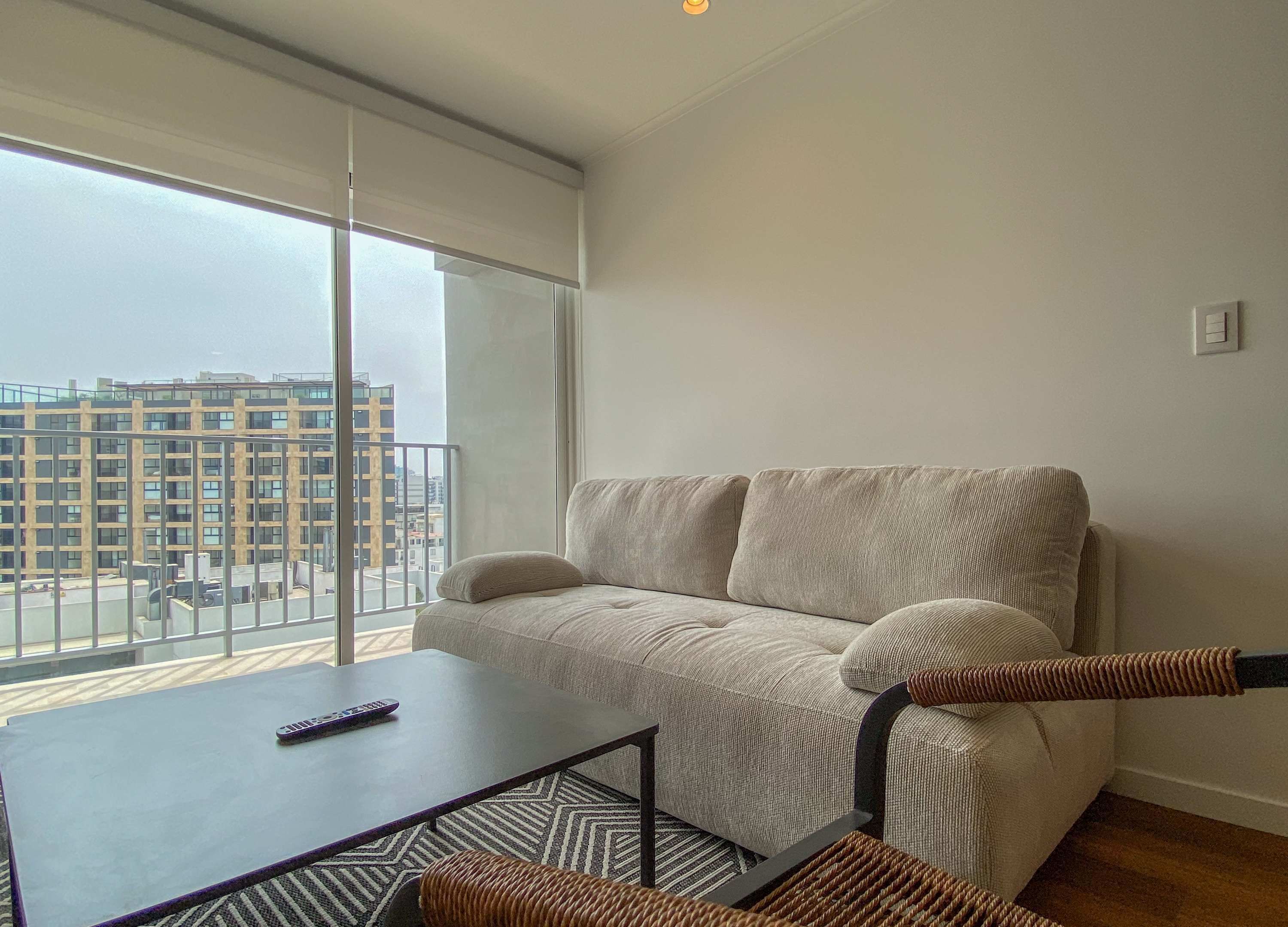 Un salon moderne avec un canapé, une petite table et une télécommande.