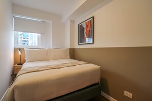 A neatly made bed with a headboard, a bedside lamp, a framed picture on the wall, and a window with blinds. - w Light-filled 2BR w Balcony in Miraflores (Lima)
