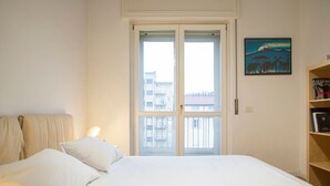 A bedroom with a bed, a door, and a painting on the wall. - Bright Ambrose I Elegant 3 Bedroom Apartment With Balconies in Milan (Milan)
