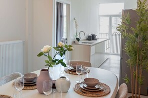 Un coin repas avec une table dressée pour quatre personnes, comprenant des bols, des verres à vin et un vase avec des fleurs.
