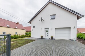 A single-story house with a white facade, a garage, and a paved driveway. - Holiday Home 'Kronseeliebe' with Private Terrace, Garden, and Wi-Fi (Lychen)