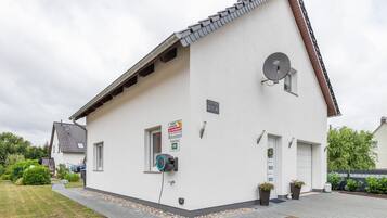 Un edificio blanco con una antena parabólica, una ventana pequeña y un letrero que indica que es una propiedad en alquiler.