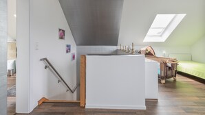 Una habitación pequeña con techo inclinado, una kitchenette, una ventana y una cama.