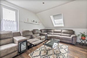 A modern living room with a sectional sofa, a glass coffee table, and a small side table. - Holiday Home 'Kronseeliebe' with Private Terrace, Garden, and Wi-Fi (Lychen)