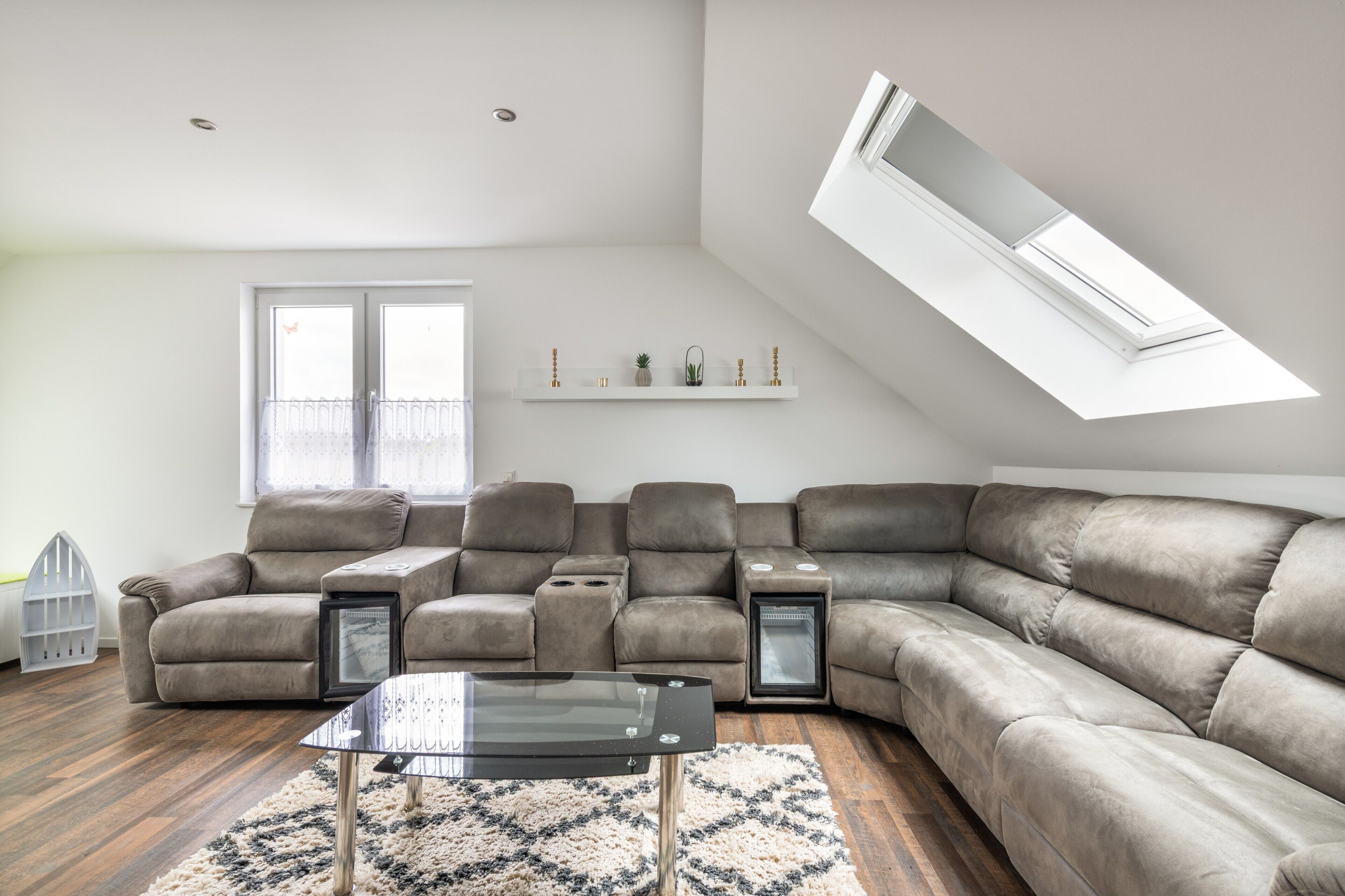 Ein modernes Wohnzimmer mit einer Eckcouch, einem Glastisch und einem Oberlicht.