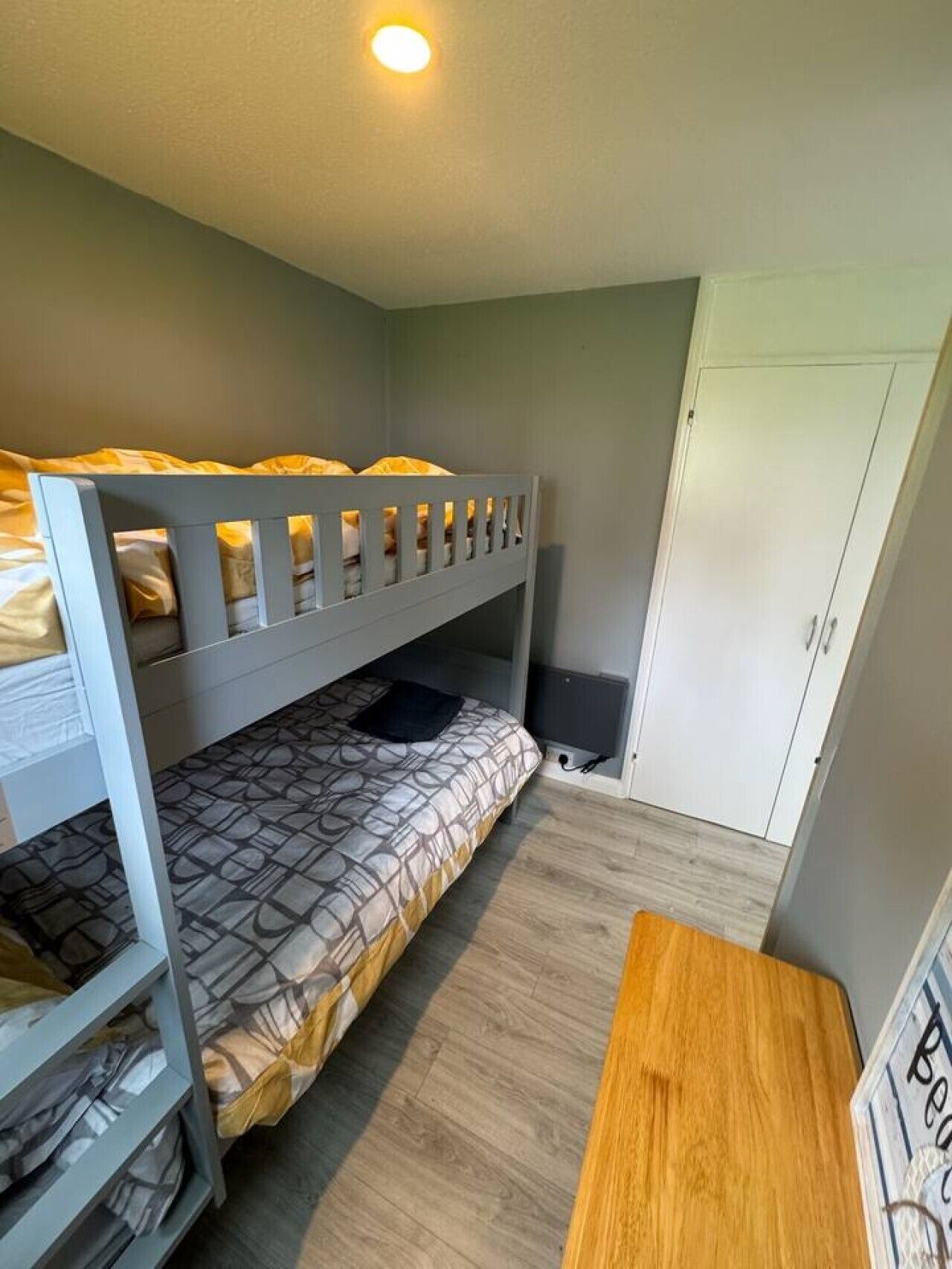 Une chambre avec un lit superposé, une armoire et un bureau.