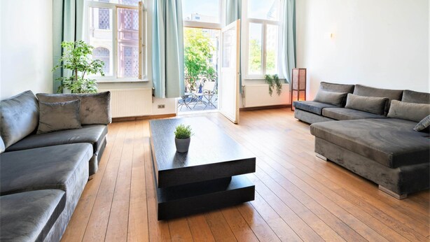 A modern living room with a sofa, a coffee table, and a view of a balcony. - 3 Bedroom Cosy Apartment (Antwerp)