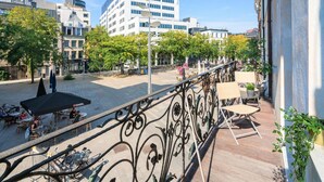 A balcony with a wrought iron railing, outdoor seating, and a view of a city street with buildings and trees. - 3 Bedroom Cosy Apartment (Antwerp)