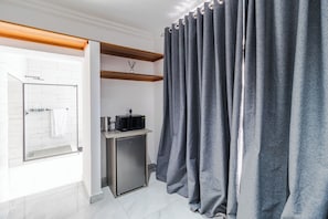 Ein Badezimmer mit Dusche, einem kleinen Schrank mit einer Mikrowelle und einem grauen Vorhang.