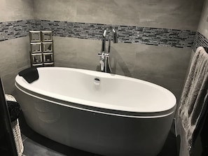Un baño moderno con una bañera independiente, un perchero para toallas y un salpicadero de azulejos.