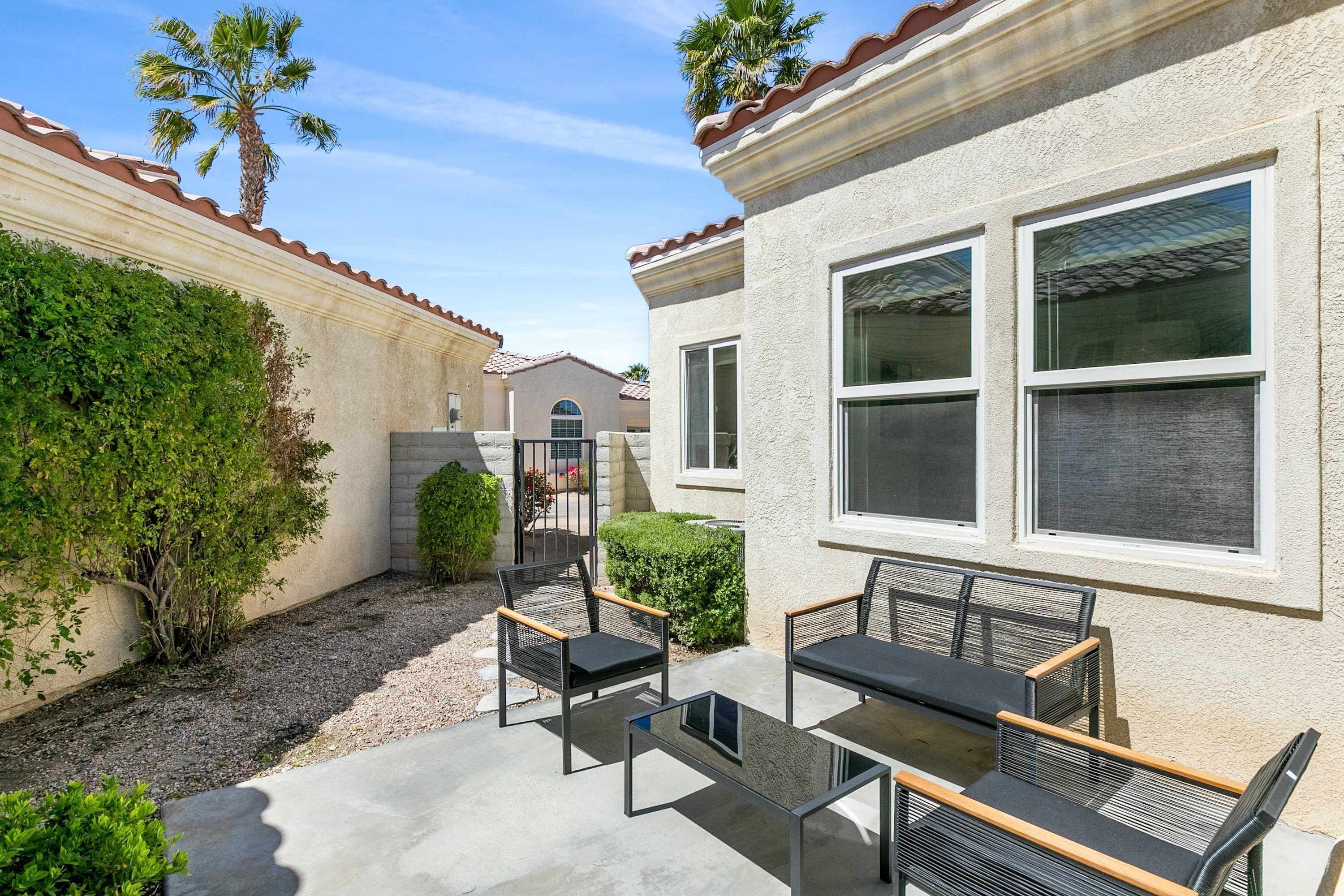 A patio with outdoor furniture, a building with large windows, and a palm tree.