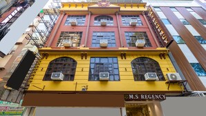 A multi-story building with a yellow facade, air conditioning units, and a sign reading 'M.S. REGENCY.' - MS REGENCY (New Delhi)
