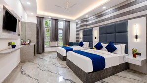A modern hotel room with two beds, a flat-screen TV, a ceiling fan, and a large window with curtains. - MS REGENCY (New Delhi)
