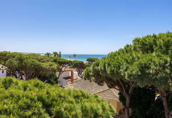 A coastal property with a view of the sea, surrounded by lush greenery and traditional architecture.