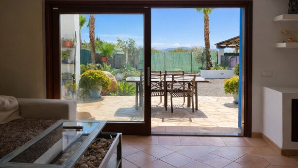 A room with a sliding glass door leading to an outdoor patio with a table and chairs. - Can Romero - Whole house with private pool near Ibiza Town (Sant Josep de sa Talaia)