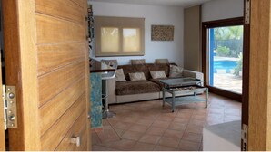 A living room with a sofa, a coffee table, and a view of a swimming pool. - Can Romero - Whole house with private pool near Ibiza Town (Sant Josep de sa Talaia)