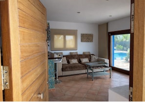 Ein Wohnzimmer mit einer Couch, einem Couchtisch und Blick auf einen Swimmingpool.