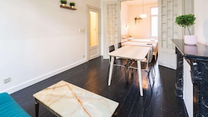 Eine moderne Küche mit Marmorarbeitsplatte, einem Essbereich mit Holztisch und -stühlen sowie einer schwarzen Marmor-Spritzschutzwand.