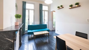 Ein modernes Zimmer mit einem blauen Sofa, einem Holztisch und einem schwarzen Schrank.