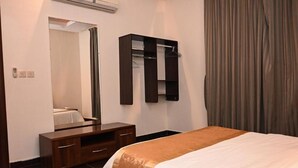 A hotel room with a bed, a dresser, a mirror, and a wardrobe. - Quiet Rooms 14  (Riyadh)