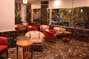 Eine Lobby mit Sitzgelegenheiten, einem Marmorboden und Blick durch große Fenster.