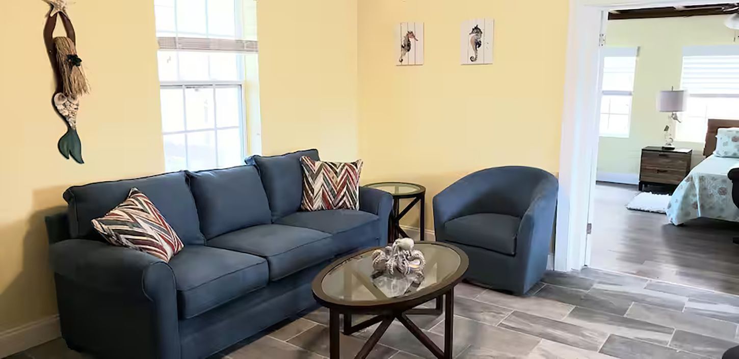 Un salon comprenant un canapé, deux fauteuils, une table basse et un élément décoratif fixé au mur.