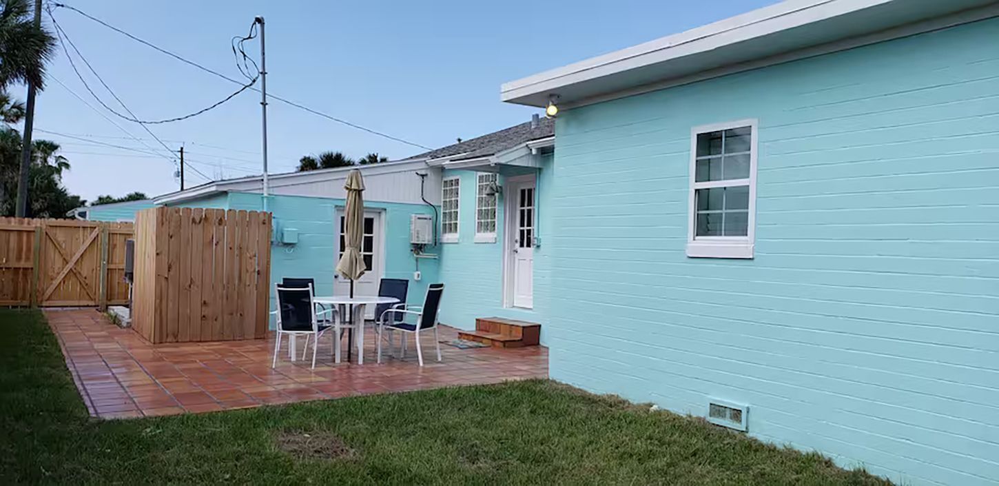 A residential property with a patio, a wooden fence, and a light blue exterior.
