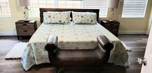 A bedroom with a bed, two nightstands, a chair, and a door. - Modern Beach Retreat - Mermaid Cottage (St. Augustine)