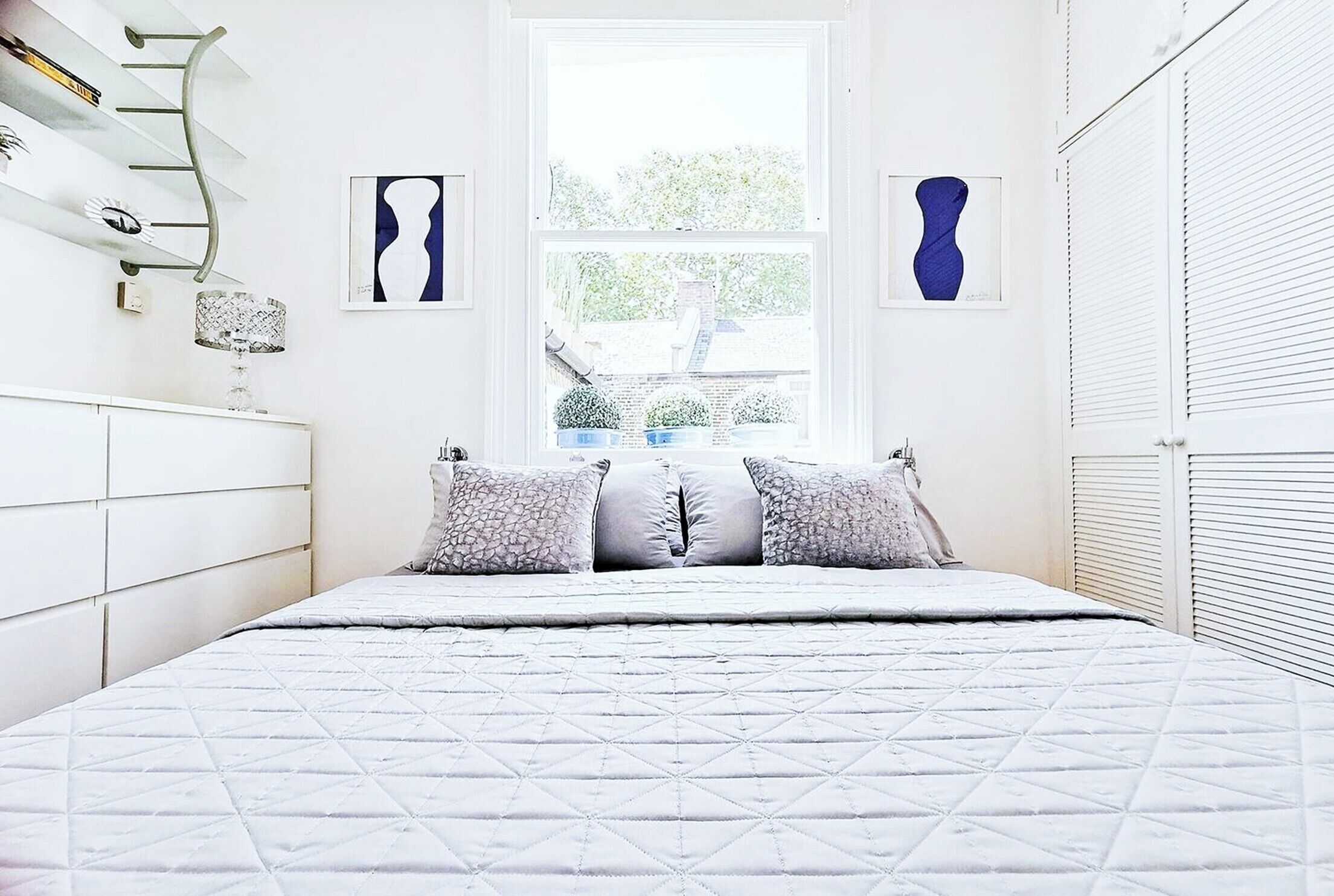 Un dormitorio con cama, ventana y armario blanco.