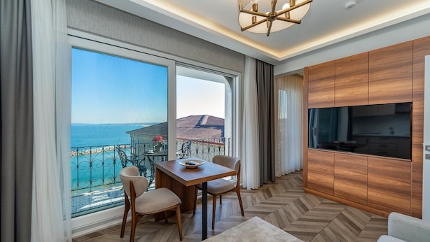 Una habitación de hotel con balcón, una mesa de comedor, sillas, un televisor y armarios de madera.
