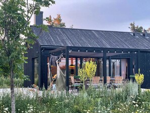 A modern building with a covered outdoor seating area and a garden. - Architect-designed house in Etelhem, Gotland (Stånga)