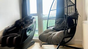 Et værelse med en massagestol, et massagebord og et vindue med gardiner.