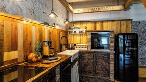 Eine rustikale Küche mit Holzwänden, einem schwarzen Kühlschrank und einer Holzausstattung mit Obstschale.