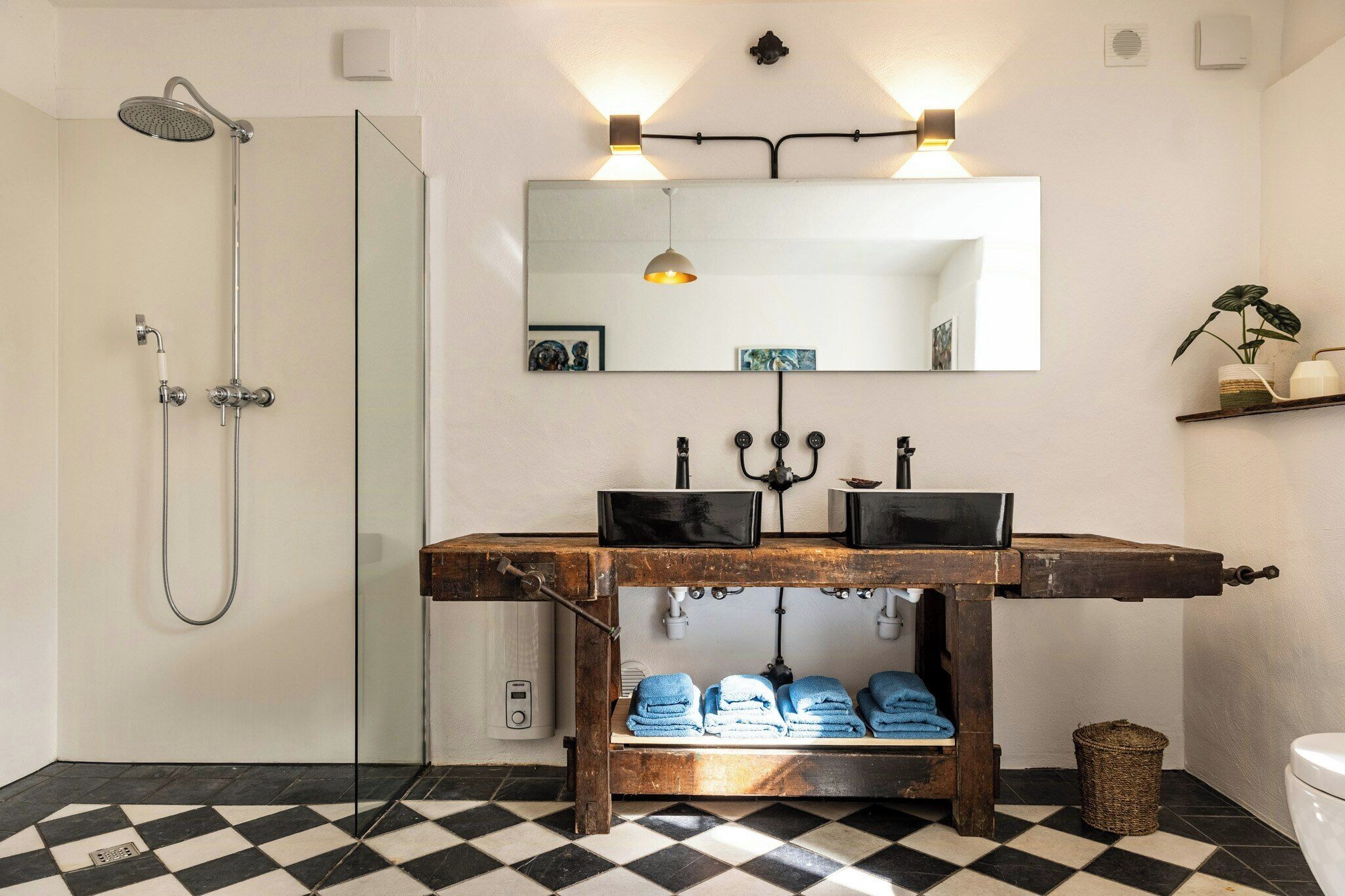 Une salle de bain avec une douche, un lavabo avec un miroir et une étagère avec des serviettes.