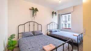 A room with two beds, a potted plant, and a window with a view of buildings. - Stay in the Heart of Antwerp (Antwerp)