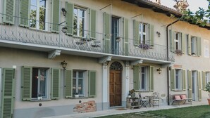 A building with a balcony, a wooden door, and a small table with chairs. - Noble residence with pool in the Langhe (Cherasco)
