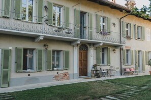 Ein Gebäude mit einem Balkon, einer Holztür und einem kleinen Tisch mit Stühlen.